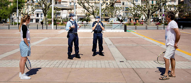 Sur le bord de mer, devant la mairie de Cannes, la police disperse un homme et une jeune fille qui jouent au tennis durant l'epidemie de coronavirus et le confinement.
