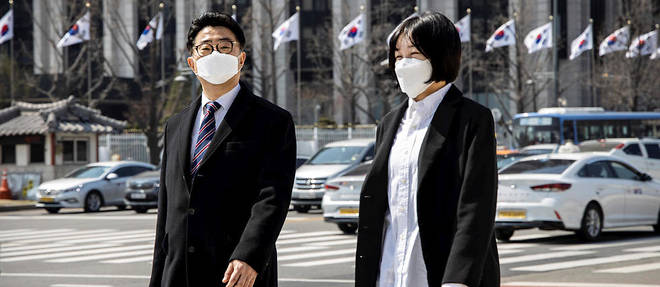 Passants portant des masques de protection sur l'avenue Sajik a proximite du palais de Gyeongbok (<< palais du Bonheur resplendissant >>), a Seoul le 23 mars 2020, pendant l'epidemie de coronavirus. 
