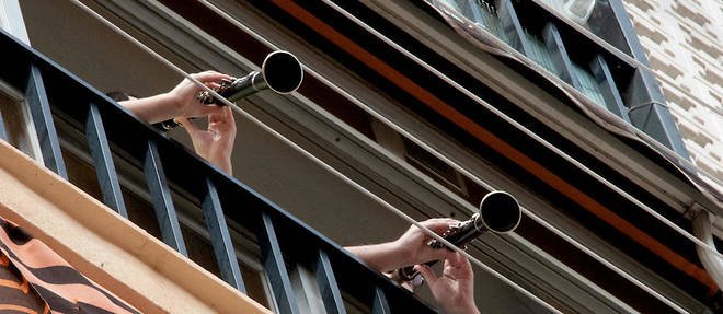 Deux personnes jouant de la clarinette sur leur balcon.
