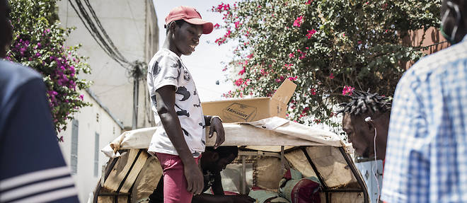De jeunes Senegalais appartenant au comite de soutien du quartier de Fann Hock, dechargent des sacs de riz le 7 mai 2020 a Dakar, a l'arriere d'une camionnette pour les distribuer aux familles ayant besoin d'aide lors de l'epidemie de coronavirus.
