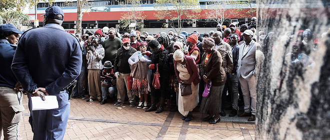 Des vendeurs informels se rassemblent devant un immeuble de bureaux municipal a Braamfontein, Johannesburg (Afrique du Sud) le 8 avril 2020, pour tenter d'obtenir un permis de travailler pendant les 21 jours du confinement national qui a debute le 27 mars 2020. 
