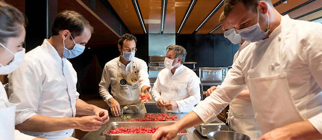 Dans la cuisine du restaurant Troisgros, Cesar Troisgros et son pere Michel (au centre) equeutent les cerises avec quatre collaborateurs.

