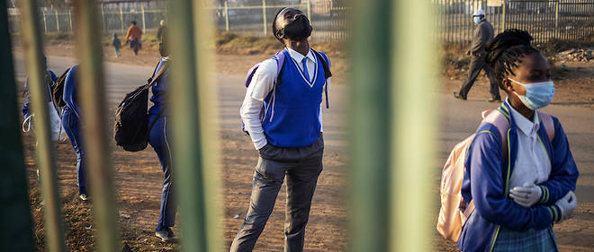 Les eleves de l'ecole secondaire Winnie Mandela font la queue devant les locaux de l'ecole avant la reprise des cours dans le canton de Tembisa, Ekurhuleni, le 8 juin 2020 apres la decision des autorites sud-africaines d'assouplir les mesures de confinement. 
