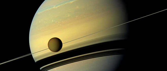 Plus grande que la planete Mercure, l'enorme lune Titan est vue ici en orbite autour de Saturne. Sous Titan se trouvent les ombres projetees par les anneaux de Saturne. Cette vue en couleurs naturelles a ete creee en combinant six images capturees par le vaisseau spatial Cassini de la Nasa le 6 mai 2012.
