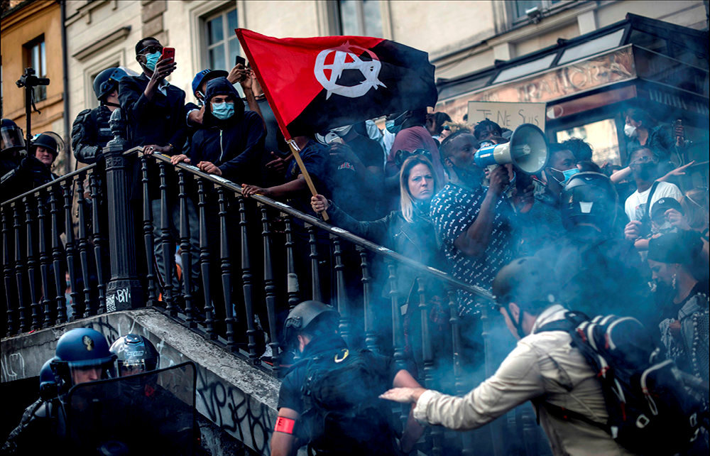 
        Debordement. Tensions a Paris, le 13 juin, place de la Republique, lors de la manifestation contre les violences policieres, lancee par le comite  Adama Traore. Ici, le drapeau rouge et noir, symbole de la mouvance anarcho-syndicaliste. La haine anti-flics s'est longtemps cantonnee au mouvement anarchiste. 