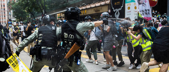 Policiers antiemeute aspergeant journalistes et manifestants lors d'un rassemblement contre la nouvelle loi de securite nationale a Hongkong le 1er juillet.  
