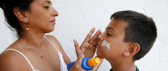 Une mere applique de la creme solaire sur le visage de son fils, en Italie.
