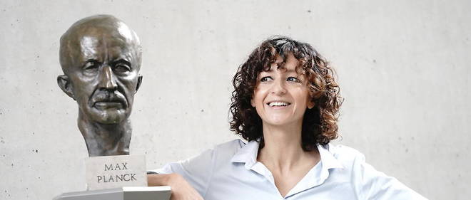 Emmanuelle Charpentier appuyee contre un buste de Max Planck.
