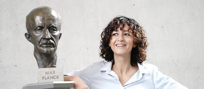 Emmanuelle Charpentier appuyee contre un buste de Max Planck.
