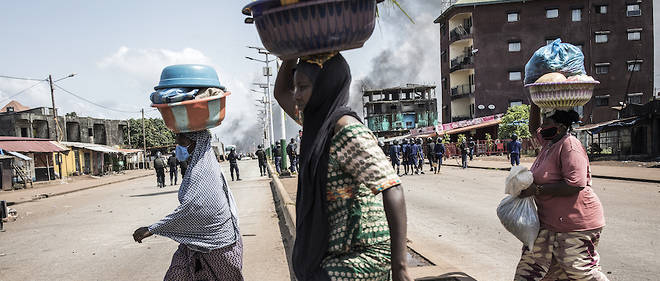 Des femmes courent en se protegeant comme elles peuvent alors que des violences ont emaille toute la matinee de ce mercredi 21 octobre a Conakry.
