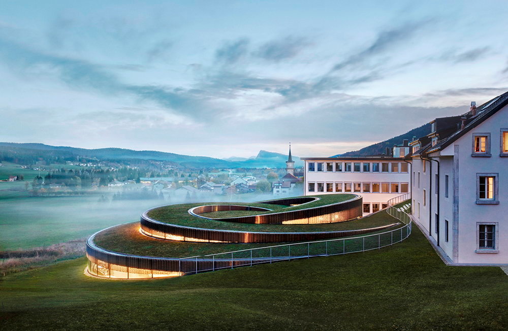 La manufacture Audemars Piguet, au Brassus (canton de Vaud, Suisse), recemment enrichie d'un spectaculaire musee-atelier en forme de spirale (imagine par le studio d'architectes danois BIG), accole a la maison des fondateurs afin d'etablir un lien entre passe, present et futur.