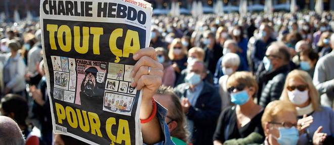 Un homme brandissant un numero de << Charlie Hebdo >> lors d'une manifestation a Toulouse apres la mort de Samuel Paty.
