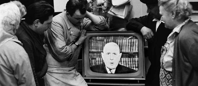 Des Parisiens ecoutent un discours du general de Gaulle a la television.

