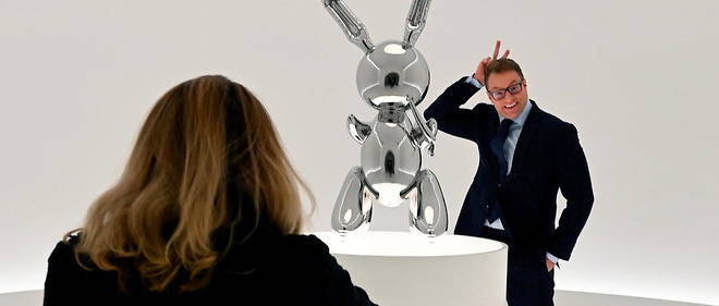 Un homme se fait protographier devant l'un des "Rabbit" de Jeff Koons, expose avant sa mise aux encheres, en mai 2019.  
