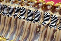            Pin-up blonde a la taille ultrafine, la premiere Barbie arbore un maillot de bain a rayures noir et blanc et le regard oblique et mysterieux de certaines femmes de l'epoque.

