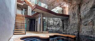  C’est par une faille que l’on accède à l’entrée, passerelle surplombant une piscine habillée de bois et de roche.   ©Loic Thebaud