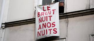 Une banderole accrochée à une fenêtre contre le tapage nocturne avec le message « Le bruit nuit à nos nuits ».
