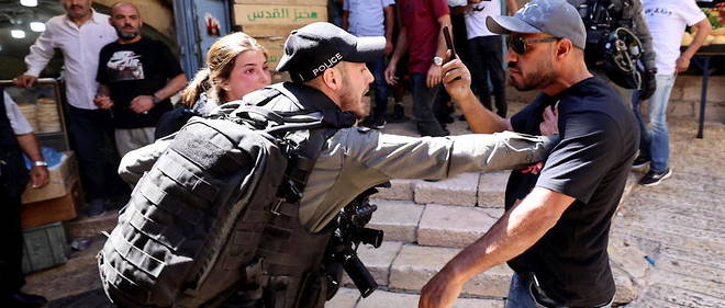 Un agent de la police israelienne des frontieres face a un manifestant palestinien a la porte de Damas, le 18 mai 2021, a Jerusalem-Est. 
