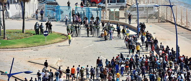 Des forces de securite marocaines face a des migrants tentant de fuir vers l'enclave espagnole de Ceuta, le 19 mai 2021.
