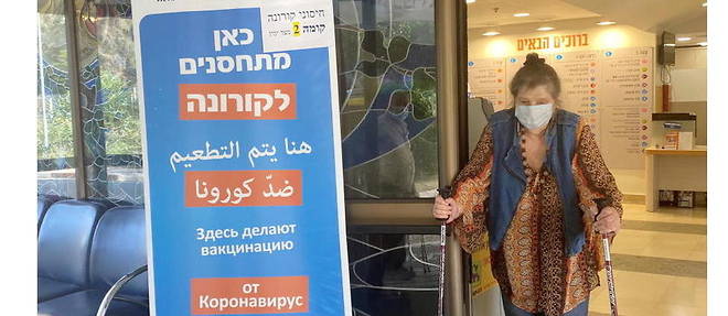 "Ici on vaccine contre le Corona", peut-on lire en hebreu, en arabe et en russe sur l'affiche posee devant le dispensaire de la caisse maladie Meouhedet, a Jerusalem. 
