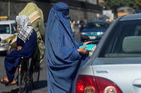 Une femme vêtue d'une burqa vend des masques dans une rue de Kaboul, le 5 septembre 2021.
