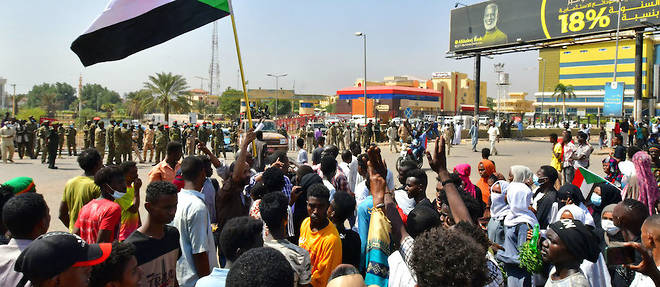 Sous une nuee de drapeaux, une foule de Soudanais campe dans les rues de Khartoum.
