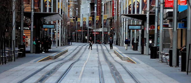 Un homme marche dans une rue deserte de Sydney, en Australie.
