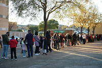 Des Espagnols font la queue pour faire vacciner leurs enfants. 
