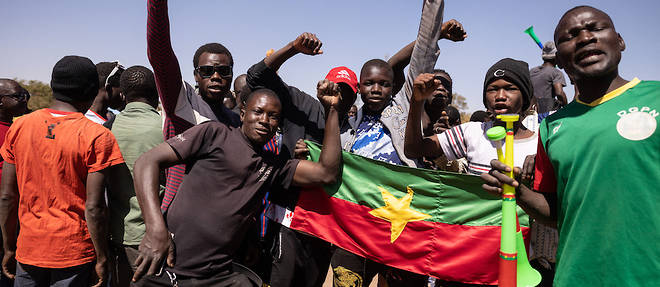 Des manifestants tiennent le drapeau national du Burkina Faso alors qu'ils se rassemblent sur la place de la Nation pour soutenir l'armee a Ouagadougou le 24 janvier 2022.
