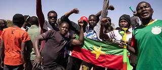Des manifestants tiennent le drapeau national du Burkina Faso alors qu'ils se rassemblent sur la place de la Nation pour soutenir l'armée à Ouagadougou le 24 janvier 2022.
