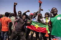 Des manifestants tiennent le drapeau national du Burkina Faso alors qu'ils se rassemblent sur la place de la Nation pour soutenir l'armée à Ouagadougou le 24 janvier 2022.
