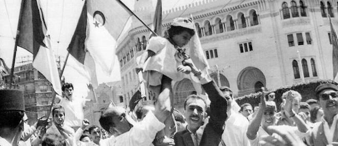 Une foule d'Algeriens manifestent leur joie en brandissant des drapeaux algeriens le 3 juillet 1962 dans le quartier europeen d'Alger devant la grande poste. L'Algerie a proclame son independance apres la signature des accords d'Evian le 18 mars 1962 et leur ratification par referendum en France le 8 avril 1962 puis en Algerie le 1er juillet 1962.
