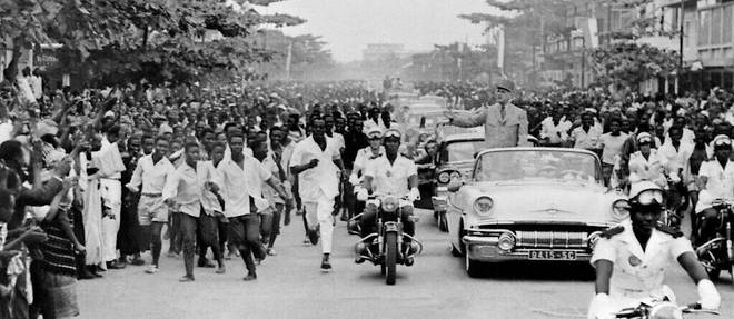 Le 26 aout 1958, a Abidjan, le president francais Charles de Gaulle, debout dans une voiture decapotable, salue la foule lors de sa visite officielle en Cote d'Ivoire, deux ans avant l'accession de la colonie a l'independance.
