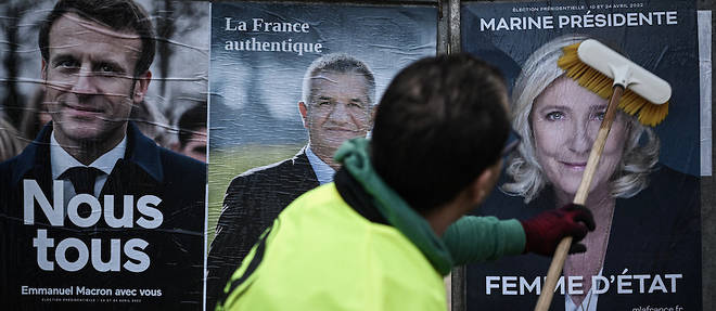Un employe d'une societe d'affichage placarde des affiches de campagne officielles des candidats a la presidence, dont a gauche celle du president candidat Emmanuel Macron et a droite Marine Le Pen du Rassemblement national (RN).
