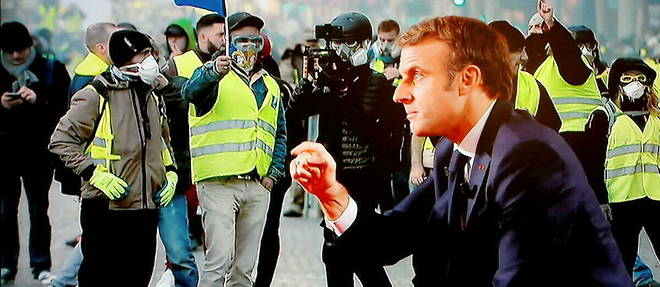 Emmanuel Macron, interroge sur TF1 en decembre 2021, devant des images de Gilets jaunes. 
