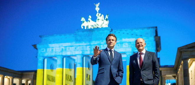 Le president francais Emmanuel Macron (a gauche) et le chancelier allemand Olaf Scholz (a droite), le 9 mai a Berlin, devant la porte de Brandebourg illuminee aux couleurs ukrainiennes.
