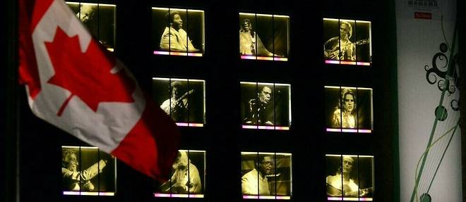 Drapeau canadien flottant devant l'immeuble orne de photgraphies des legendes du jazz durant le Festival de jazz de Montreal,  le 2 juillet 2018.
