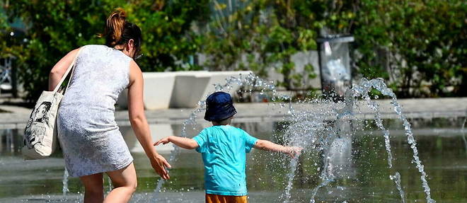 Une maman et son enfant profitant de la fraicheur des fontaines a Montpellier, mardi 14 juin 2022.
