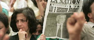 Une femme brandit une page du journal « La Nation » intitulé « Qui a assassiné Boudiaf ? », le 1 juillet 1992 à Alger lors des obsèques du président algérien Mohamed Boudiaf, assassiné le 29 juin à Annaba au sud de l'Algérie.

