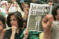 Une femme brandit une page du journal << La Nation >> intitule << Qui a assassine Boudiaf ? >>, le 1 juillet 1992 a Alger lors des obseques du president algerien Mohamed Boudiaf, assassine le 29 juin a Annaba au sud de l'Algerie.
