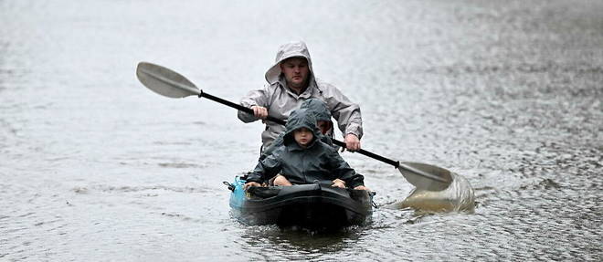 Des gens font du kayak le long d'une rue inondee, depuis le debordement de la riviere Hawkesbury, en raison de pluies torrentielles dans la banlieue de Windsor a Sydney le 4 juillet 2022. 
 
