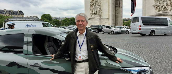 Jean-Claude Narcy devant l'Arc de Triomphe avec une voiture << customise >> militaire.
