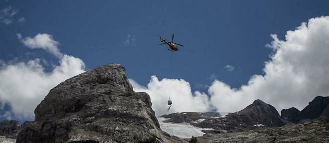 Un helicoptere de sauvetage survole le 4 juillet 2022 le glacier qui s'est effondre la veille sur la montagne de Marmolada, la plus haute des Dolomites, un jour apres qu'une temperature record de 10 degres Celsius (50 degres Fahrenheit) a ete enregistree au sommet du glacier.
