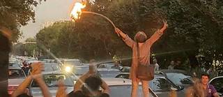 Une manifestante iranienne dévoilée brûle son foulard, suscitant les acclamations de la foule.

