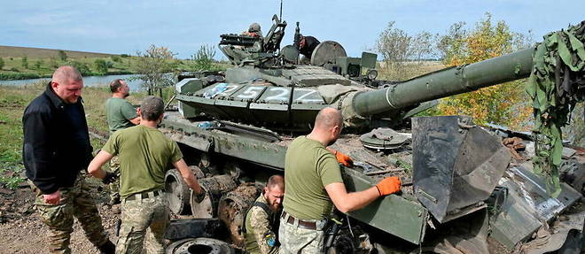 Des soldats ukrainiens s'affairent autour d'un tank abandonne par les troupes russes dans la region de Kharkiv.
