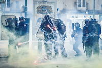 Des membres des forces de l'ordre font face à des jets de feu d'artifice lors des manifestations du 1 er  mai 2022 à Nantes.
