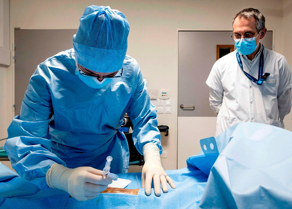 
        Seringue. Le Dr Cecile Batailler, chirurgienne orthopediste, procede a l'injection de phages directement dans le lieu de l'infection, sous le regard du Pr Ferry, a l'hopital de la Croix-Rousse le 17 fevrier 2022.