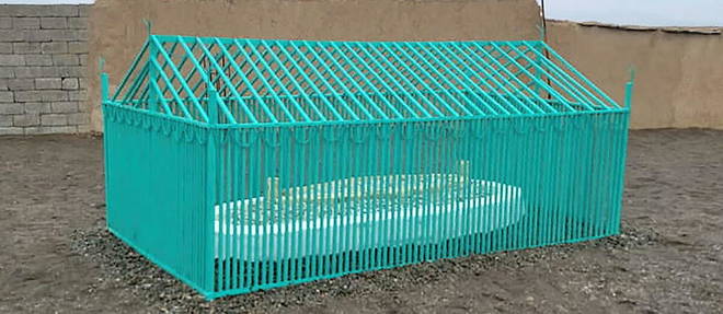 Le mollah Omar repose dans une simple tombe blanche protegee par une cage en fer verte. 
