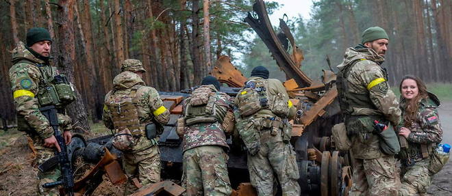 Soldats ukrainiens et combattants volontaires inspectant un char russe detruit, dans l'est de l'Ukraine.  

