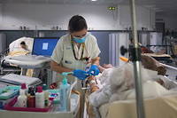 Une infirmiere preleve du sang sur une personne agee aux urgences.

